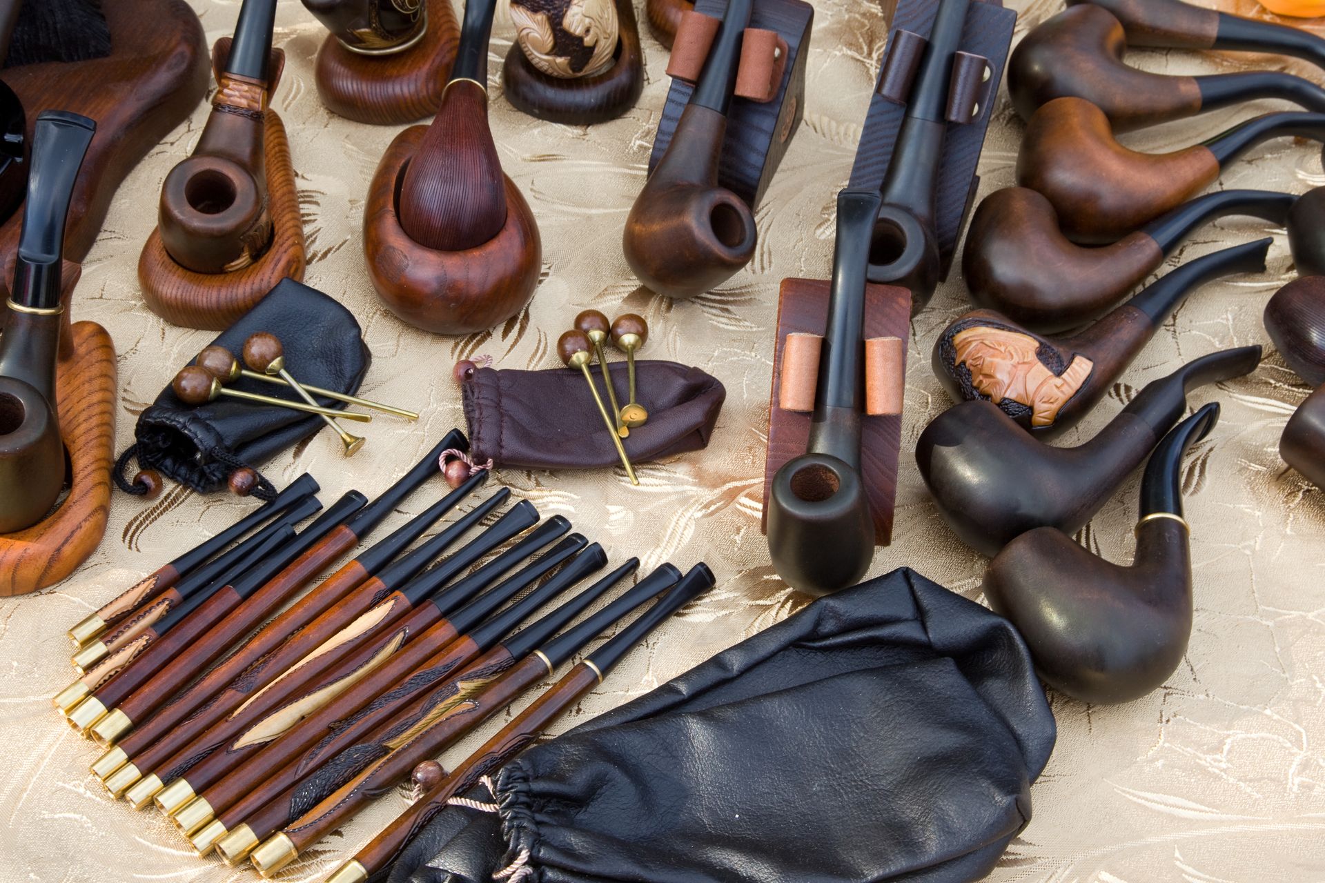 Assorted tobacco pipes and pipe cleaners displayed on a table, with a black pouch.