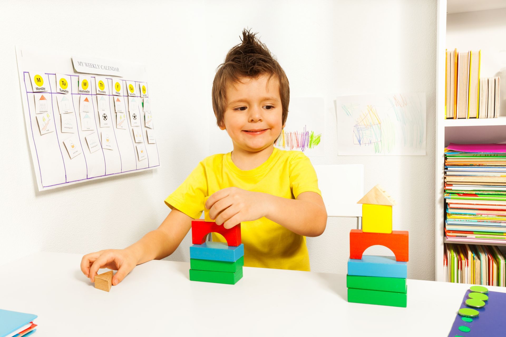 Boy with spiky hair building with colorful blocks at a table.
