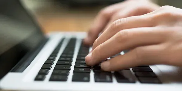 Hands typing on a laptop keyboard.