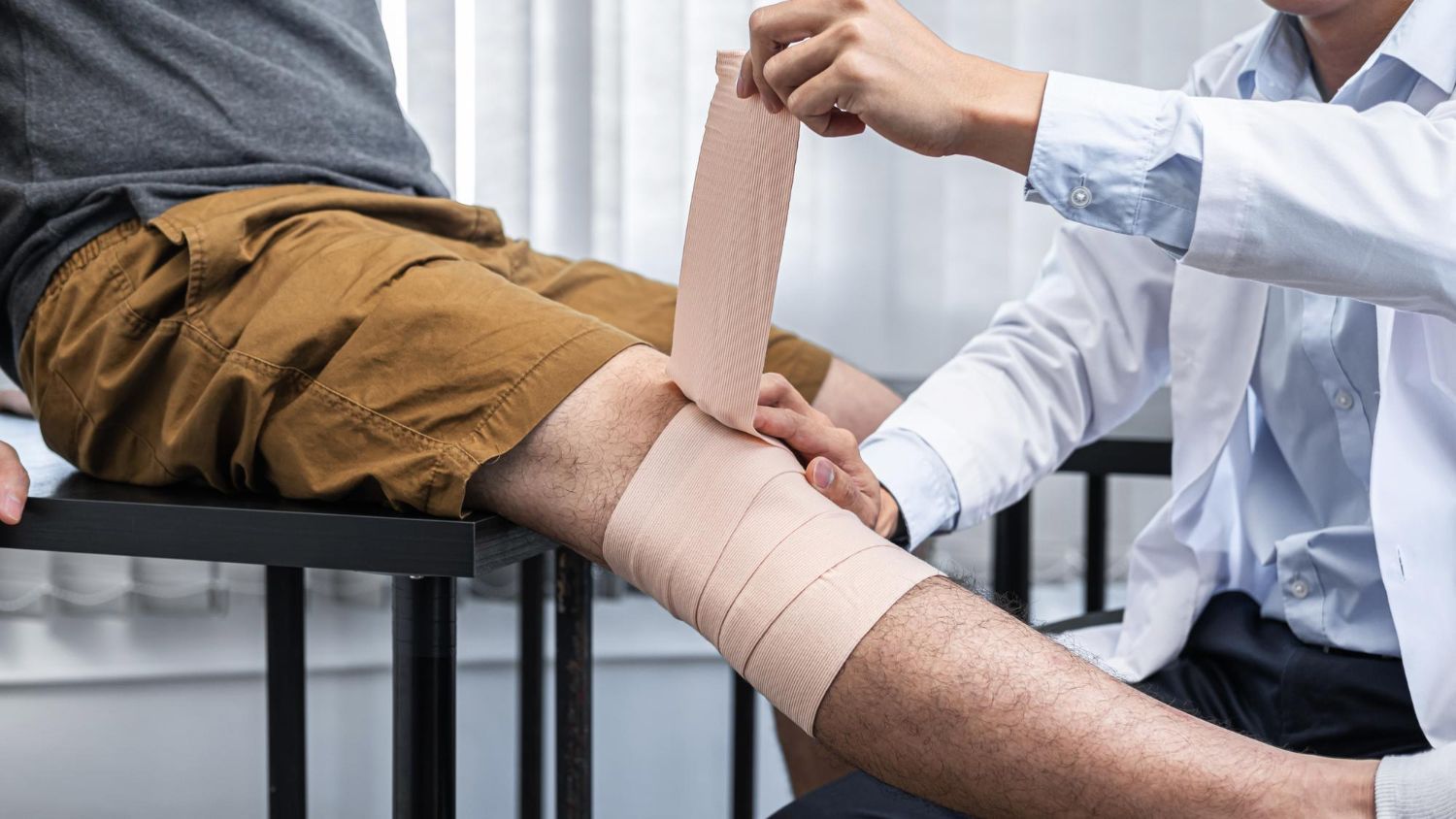 Medical professional assists a patient with a dumbbell exercise in a doctor's office.