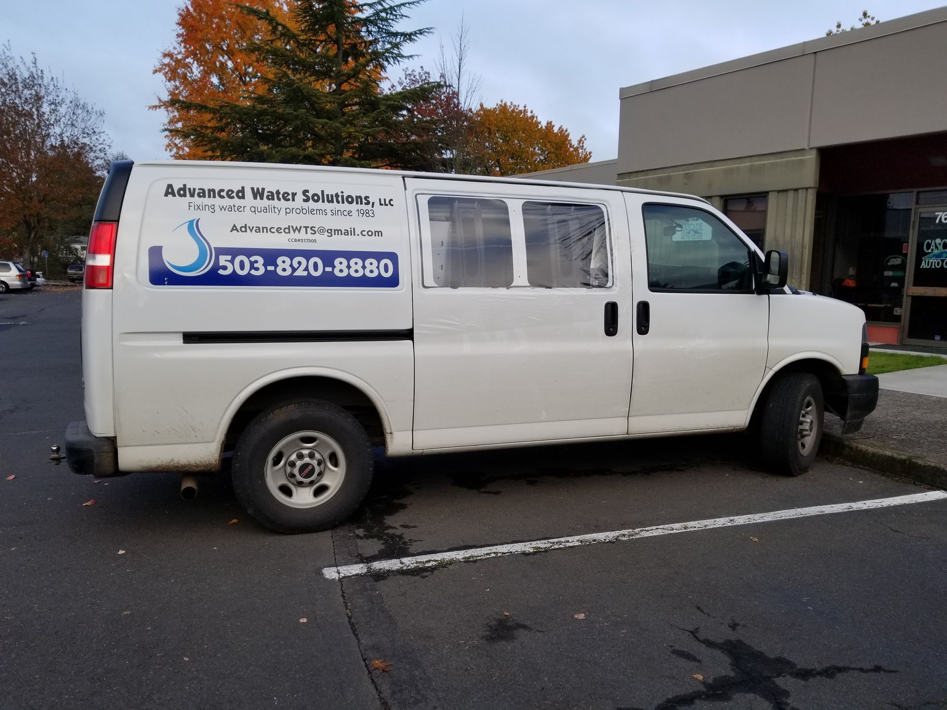 White work van with “Alderwood Water Services” sign and phone number parked outside a building.