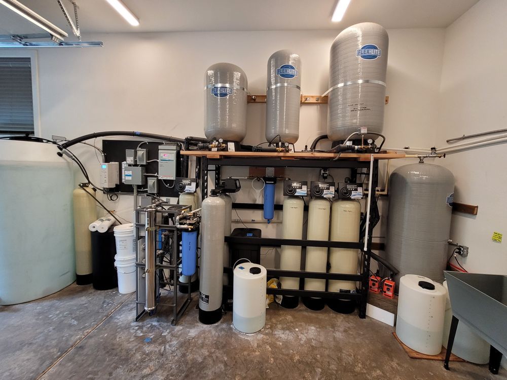 Industrial water filtration equipment with tanks, pipes, and filters in a utility room