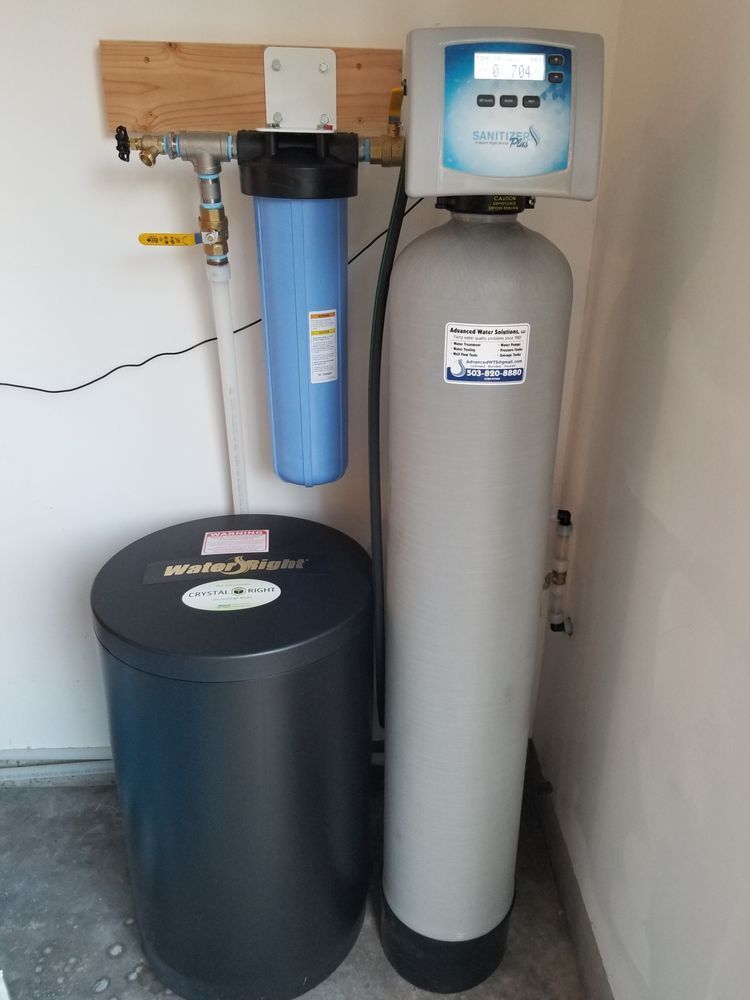 Water softener system with two tall tanks and control valves in a utility room
