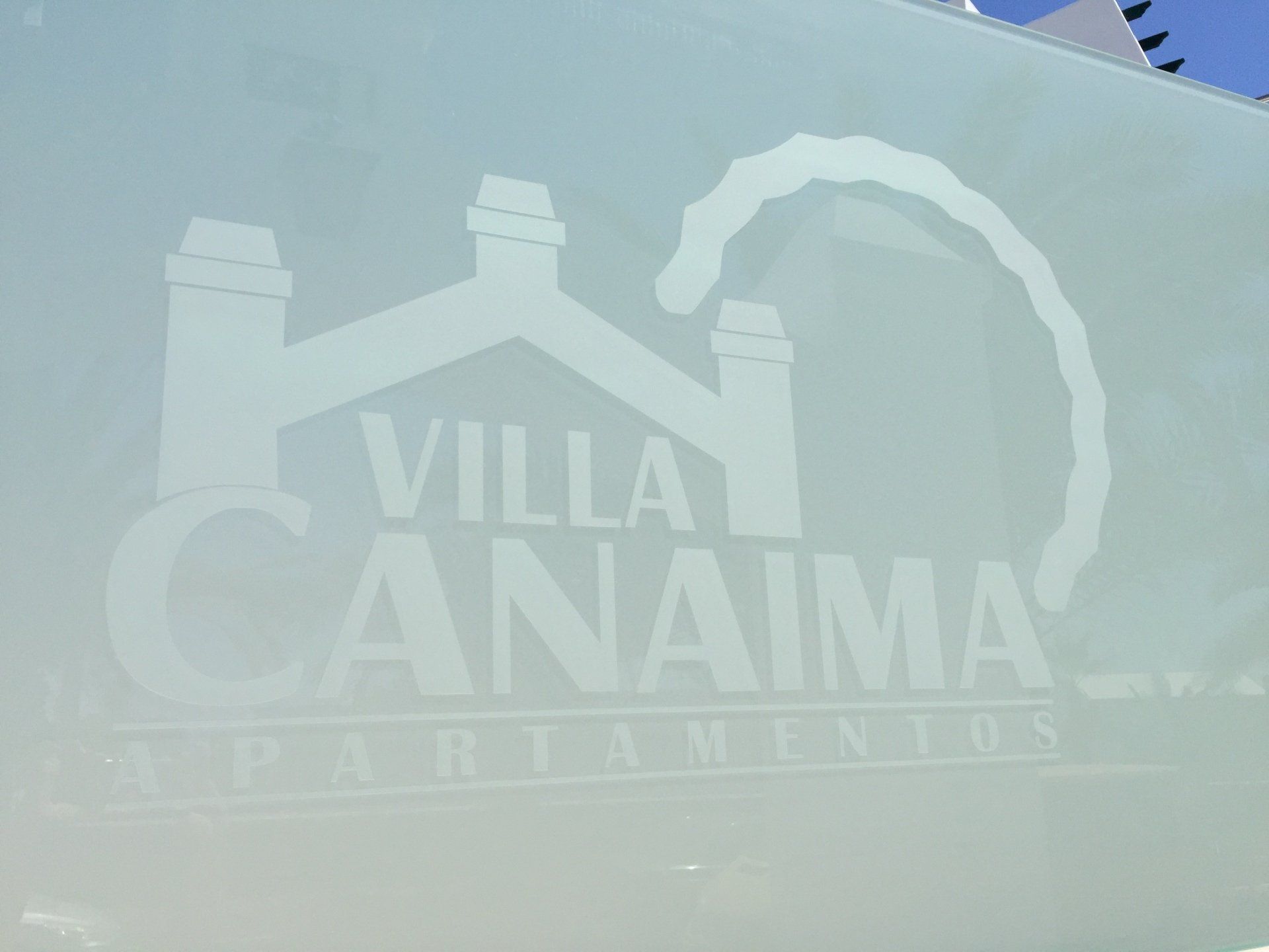 Letrero de Villa Canaima Apartamentos con logo de casa y una palmera.