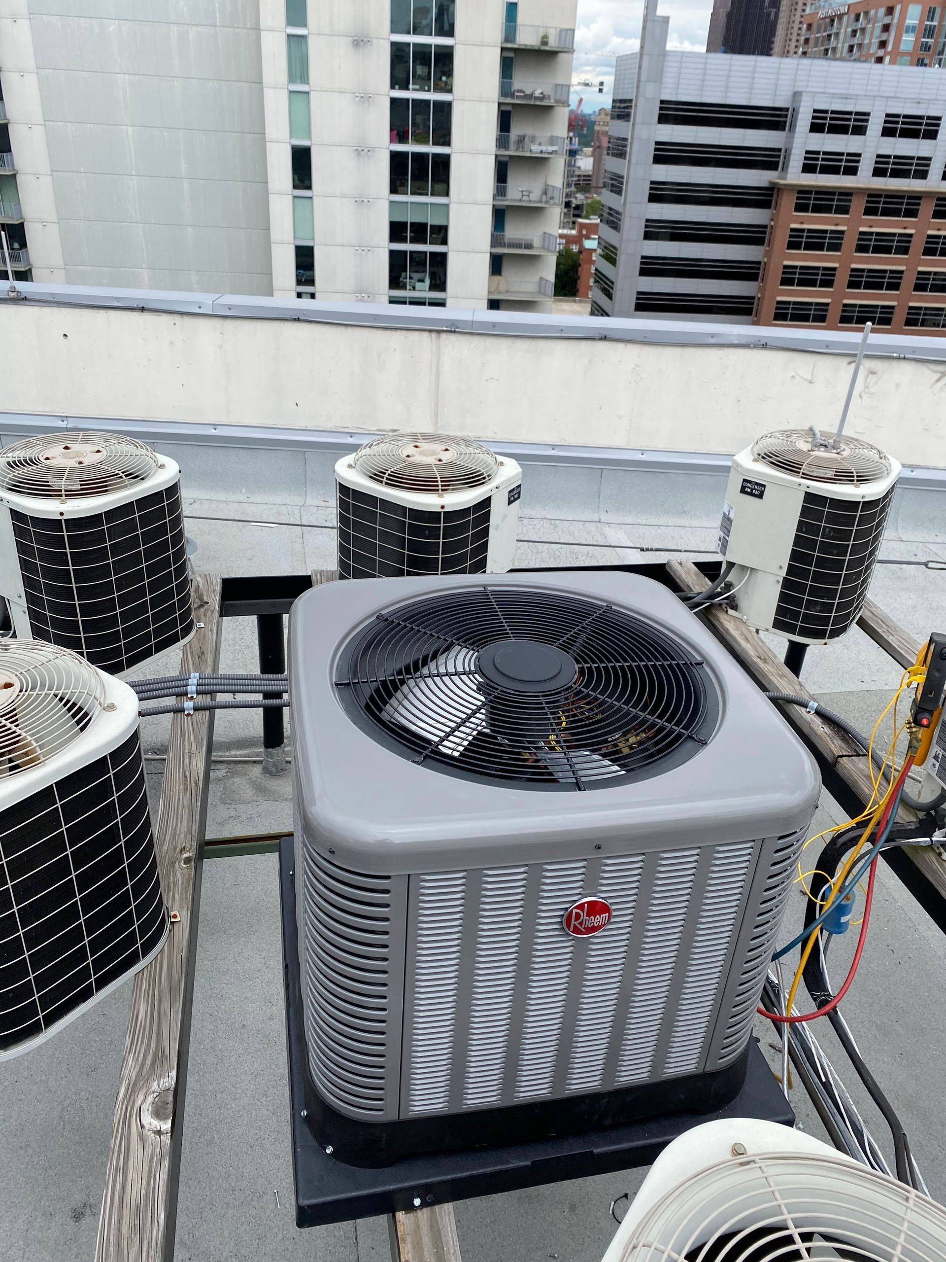 A rooftop setting featuring several industrial HVAC condenser units, including a prominent central square gray unit.