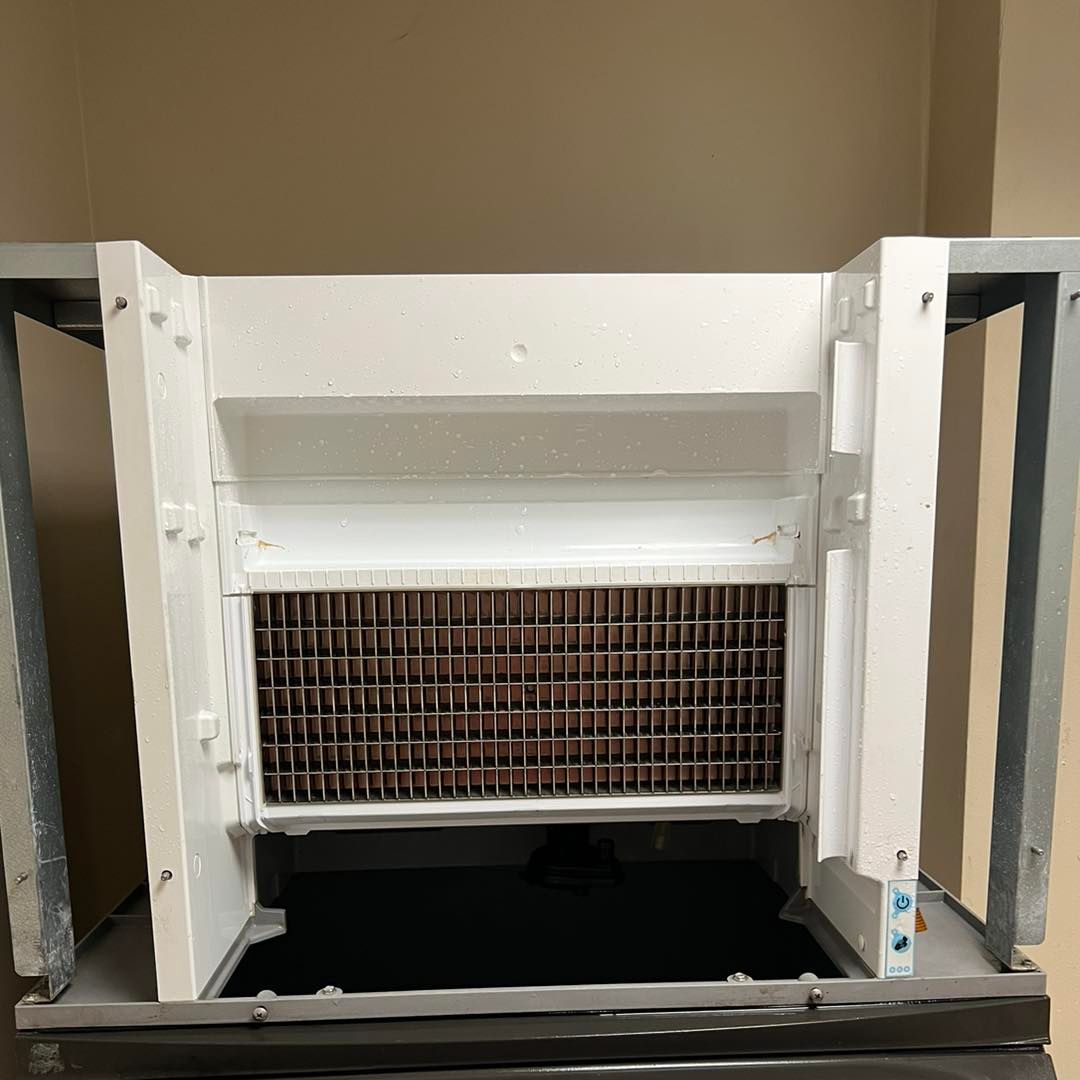 An exposed ice-making component inside a freezer, featuring a grid-patterned metal evaporator coil set in white casing.