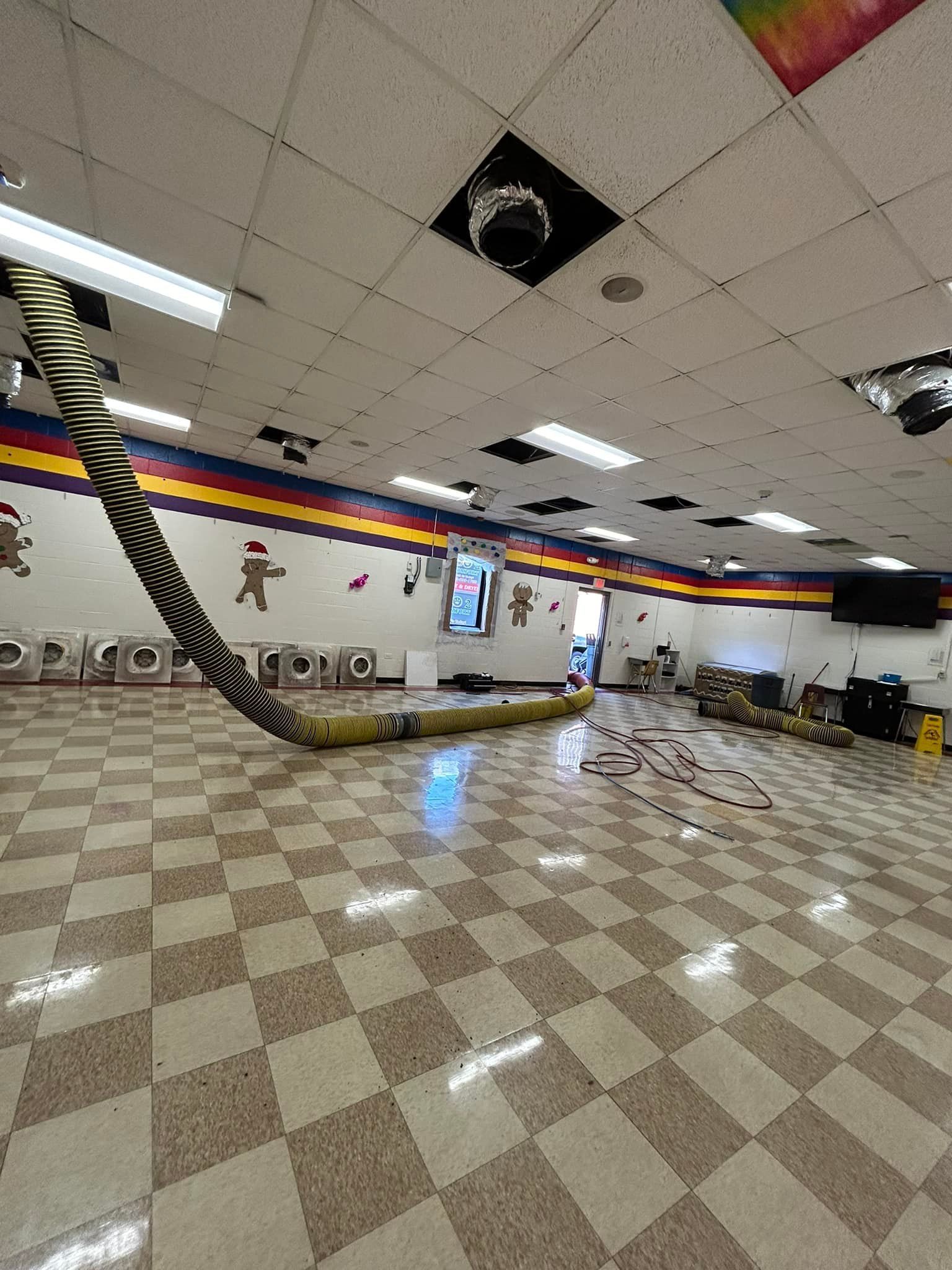 A large yellow and black striped fabric tunnel snakes across a checkered floor in a bright, decorated room.
