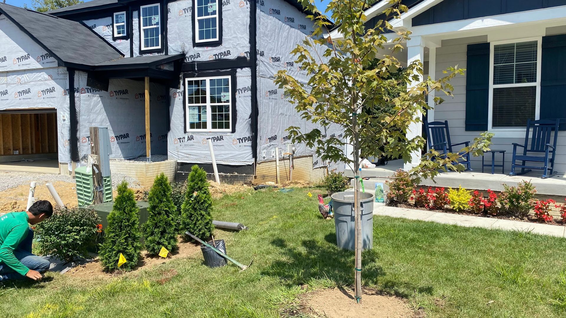 Man planting shrubs in front yard of new houses.