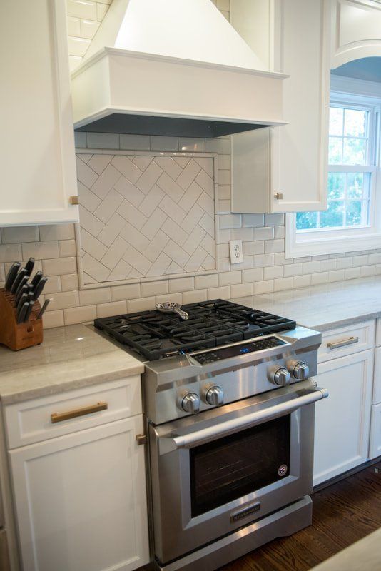 Modern kitchen with white cabinets, stainless steel gas range, and tiled backsplash