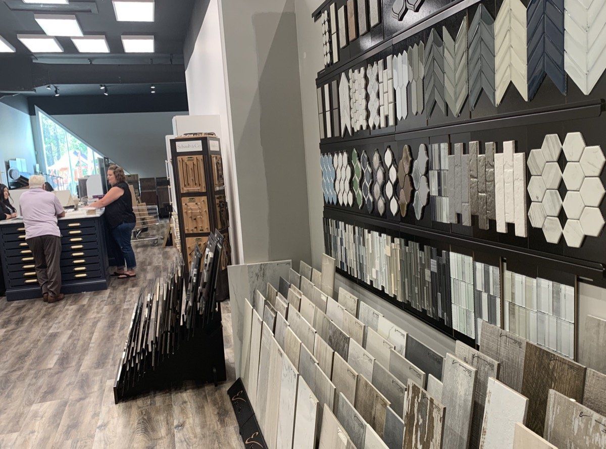 Tile showroom aisle with wall-mounted sample boards and customers browsing in the distance