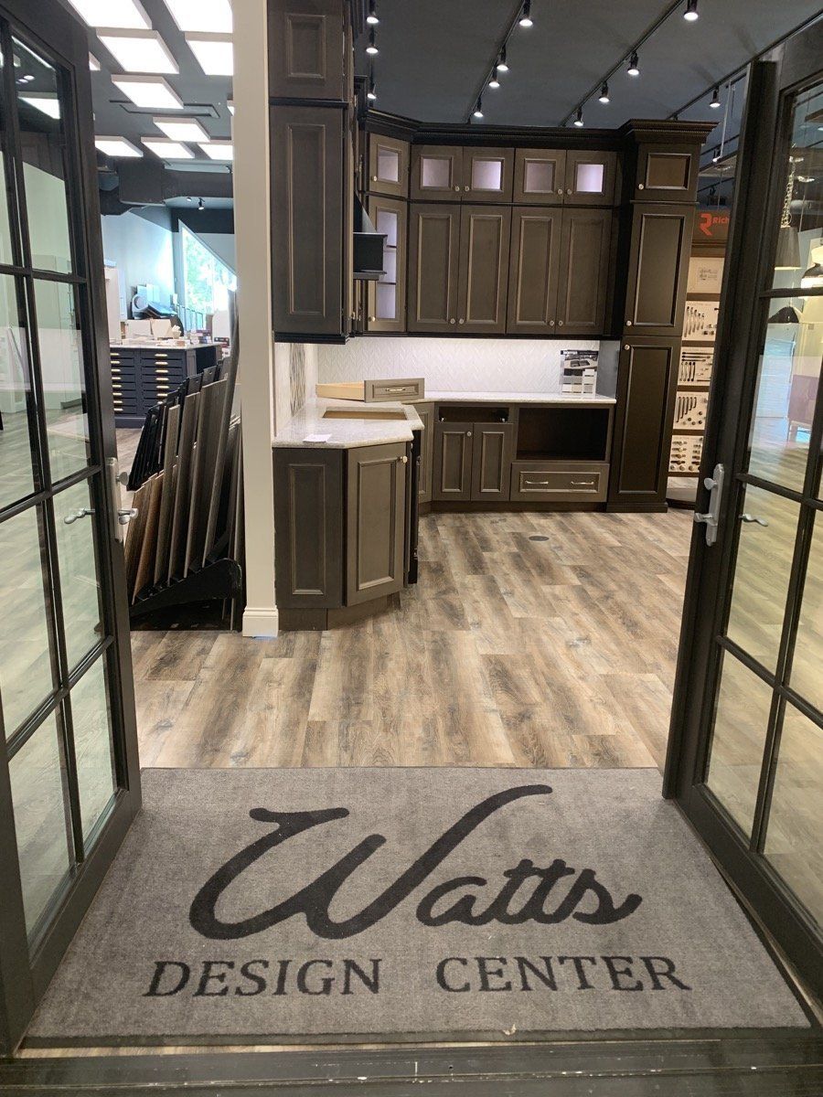 Watts Design Center showroom entrance with dark wood cabinets, light flooring, and a branded floor mat