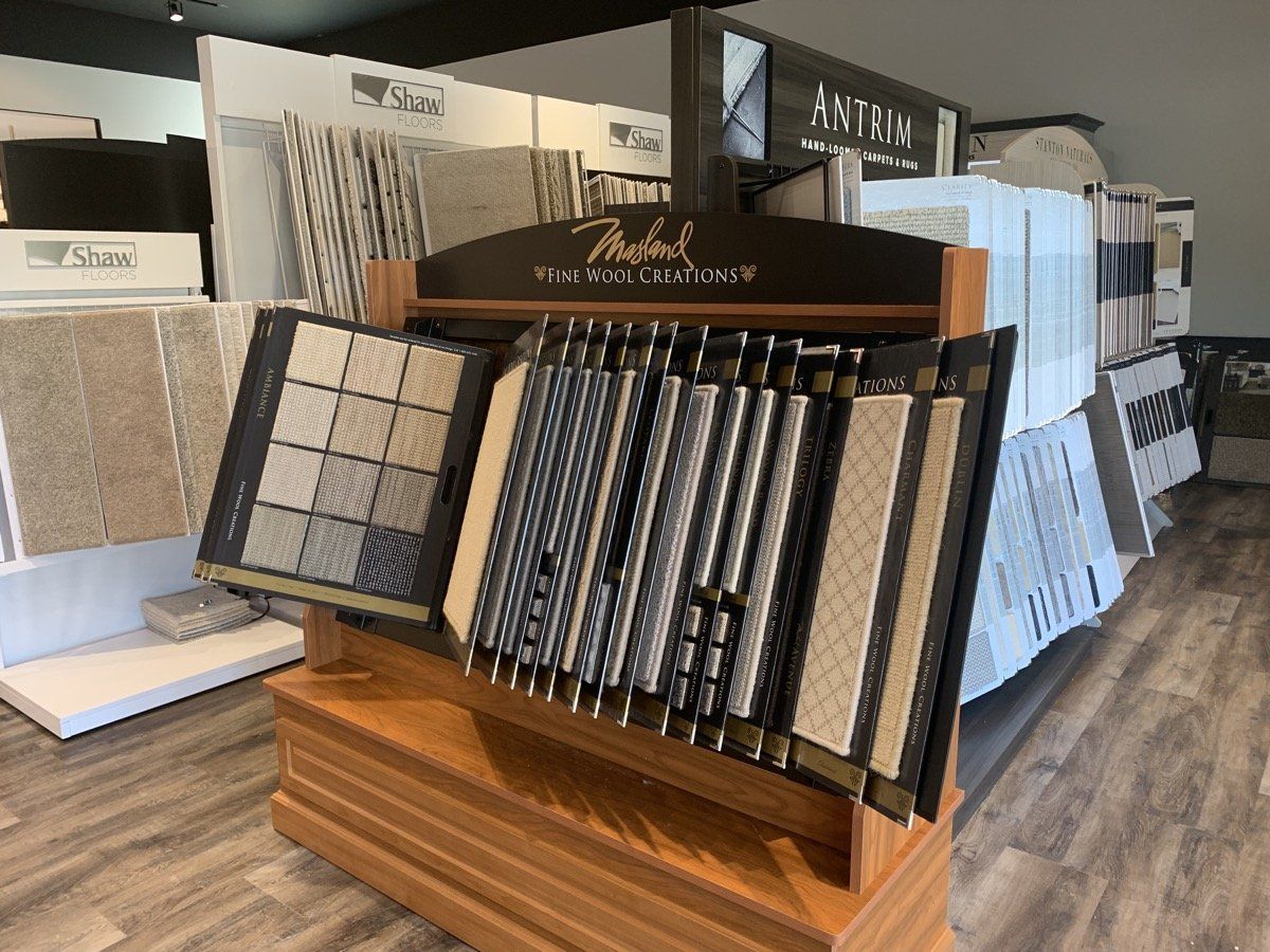 Tile and flooring display racks in a showroom, with samples of wood, carpet, and stone finishes.