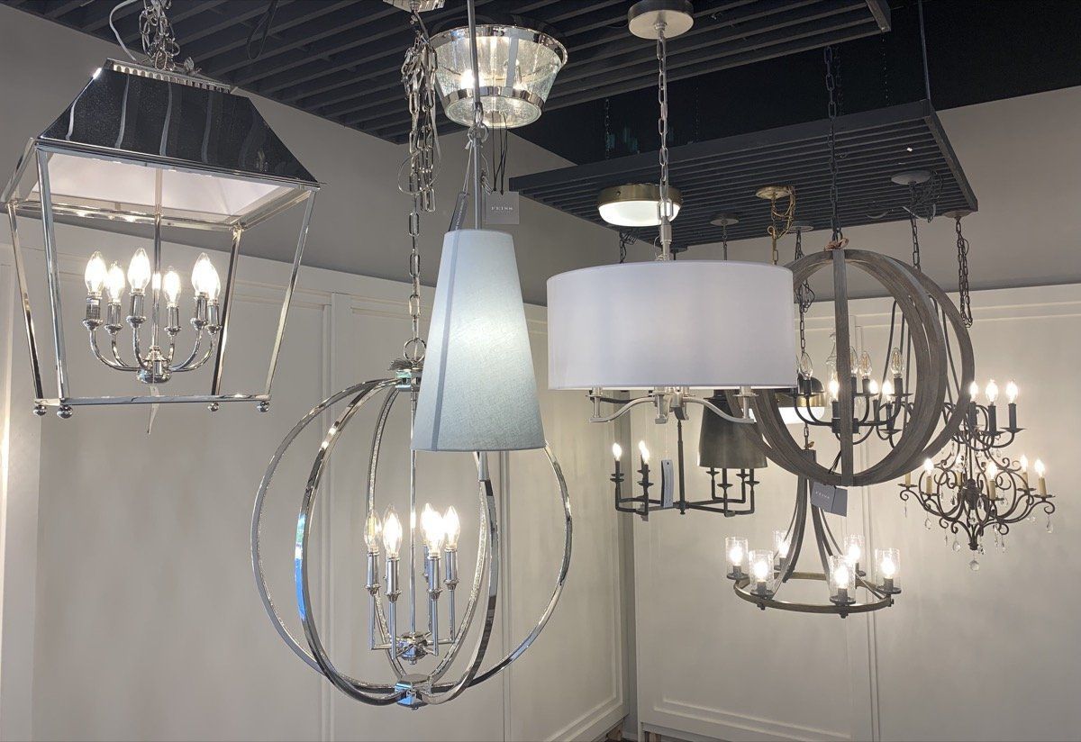 Assorted modern chandeliers and pendant lights hanging from a showroom ceiling