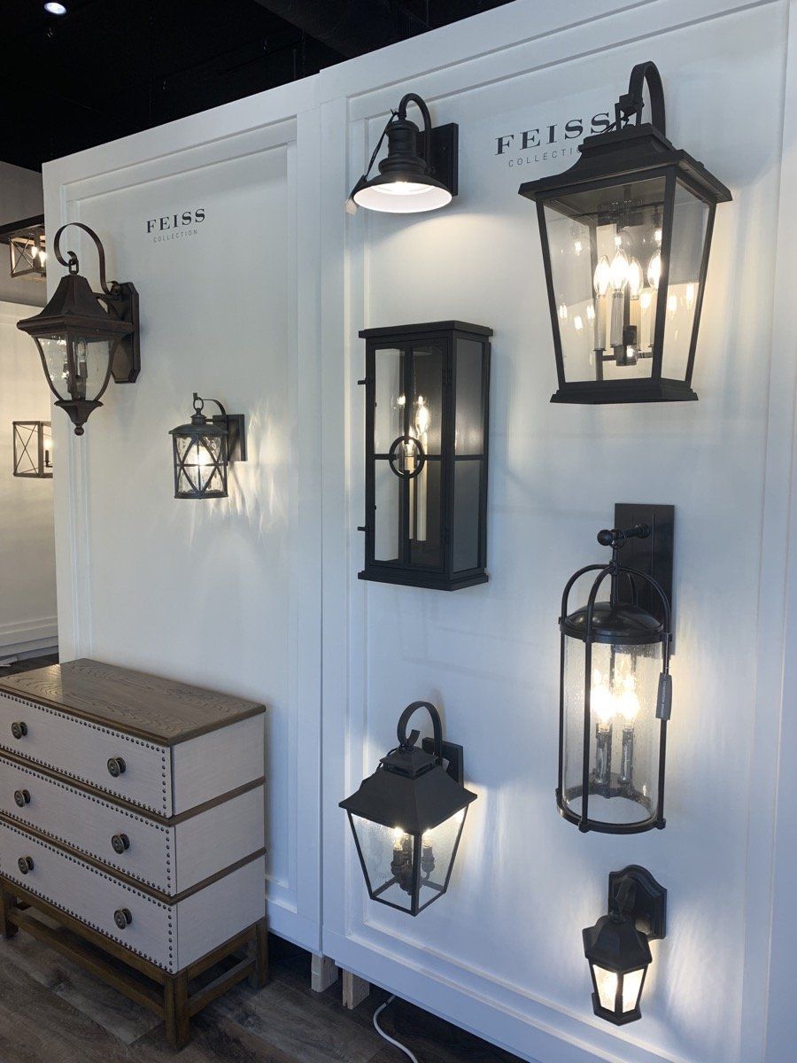 Display of black lantern wall sconces on a white wall above a small chest of drawers