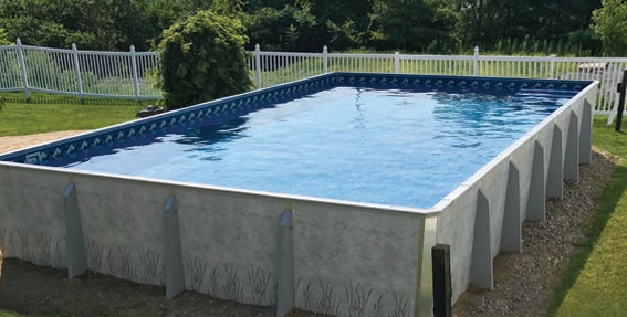 Above-ground pool with blue water in a grassy backyard, surrounded by a light-colored wall and fence.