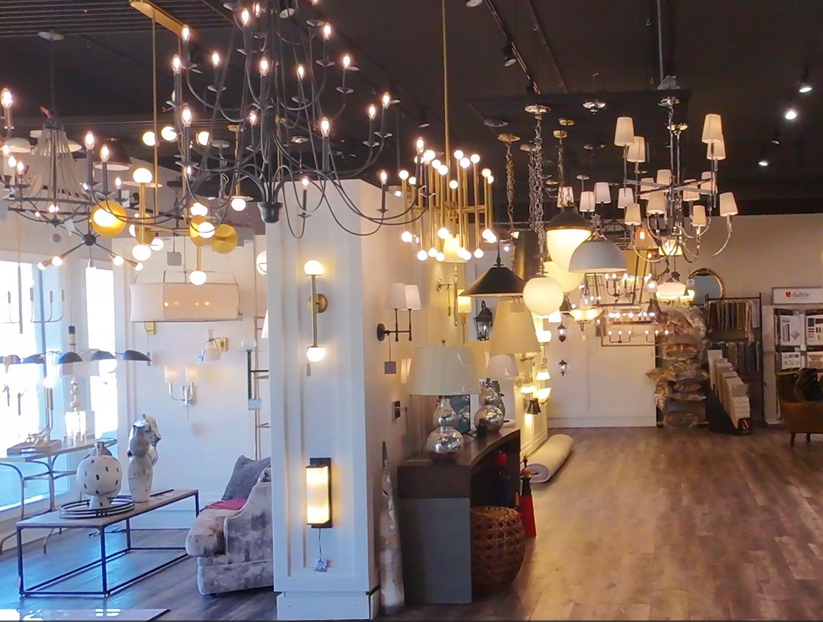Modern lighting showroom with many hanging pendant lights and wooden floors