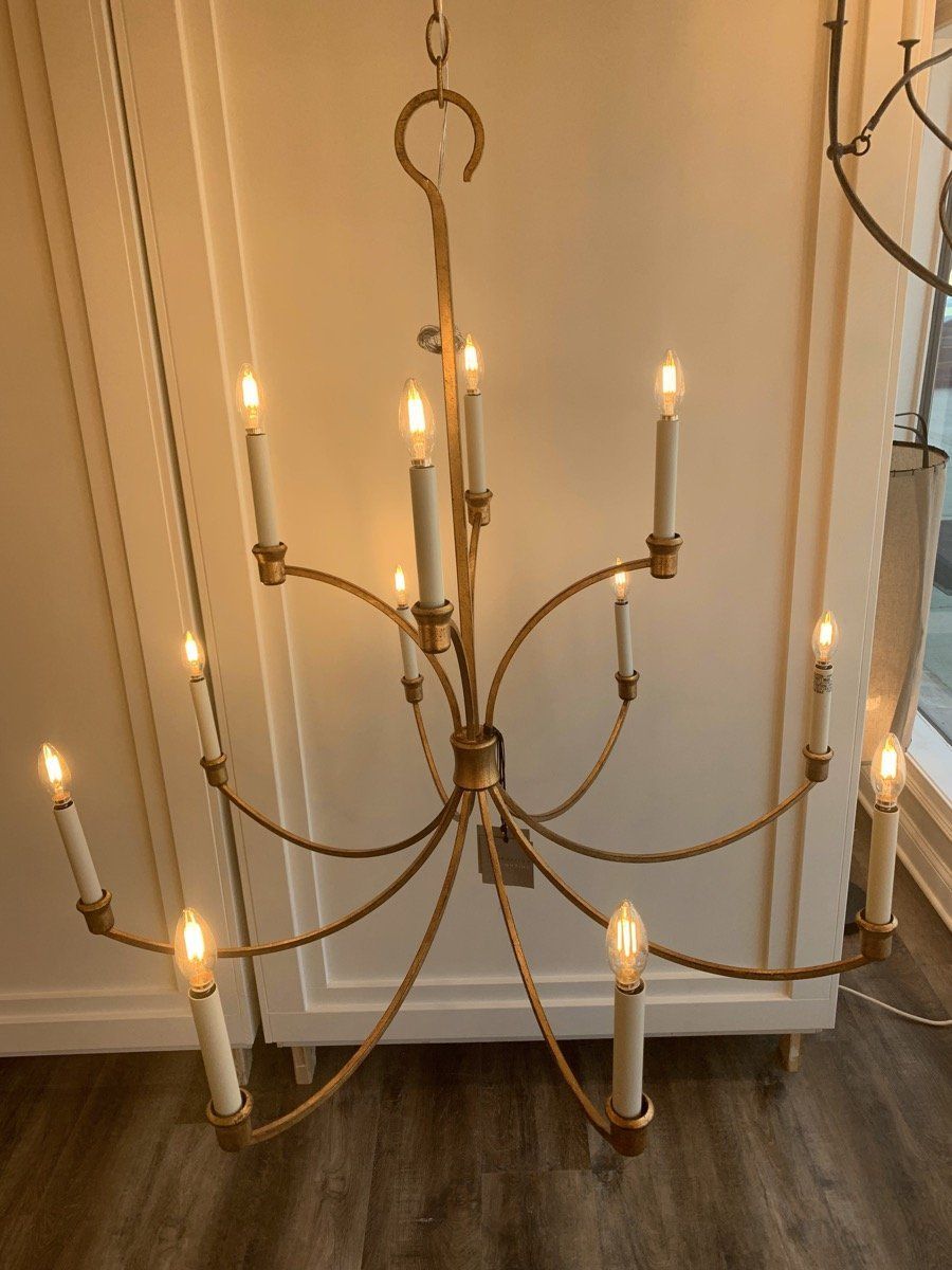 Elegant brass chandelier with lit candle-style bulbs hanging indoors over a hardwood floor