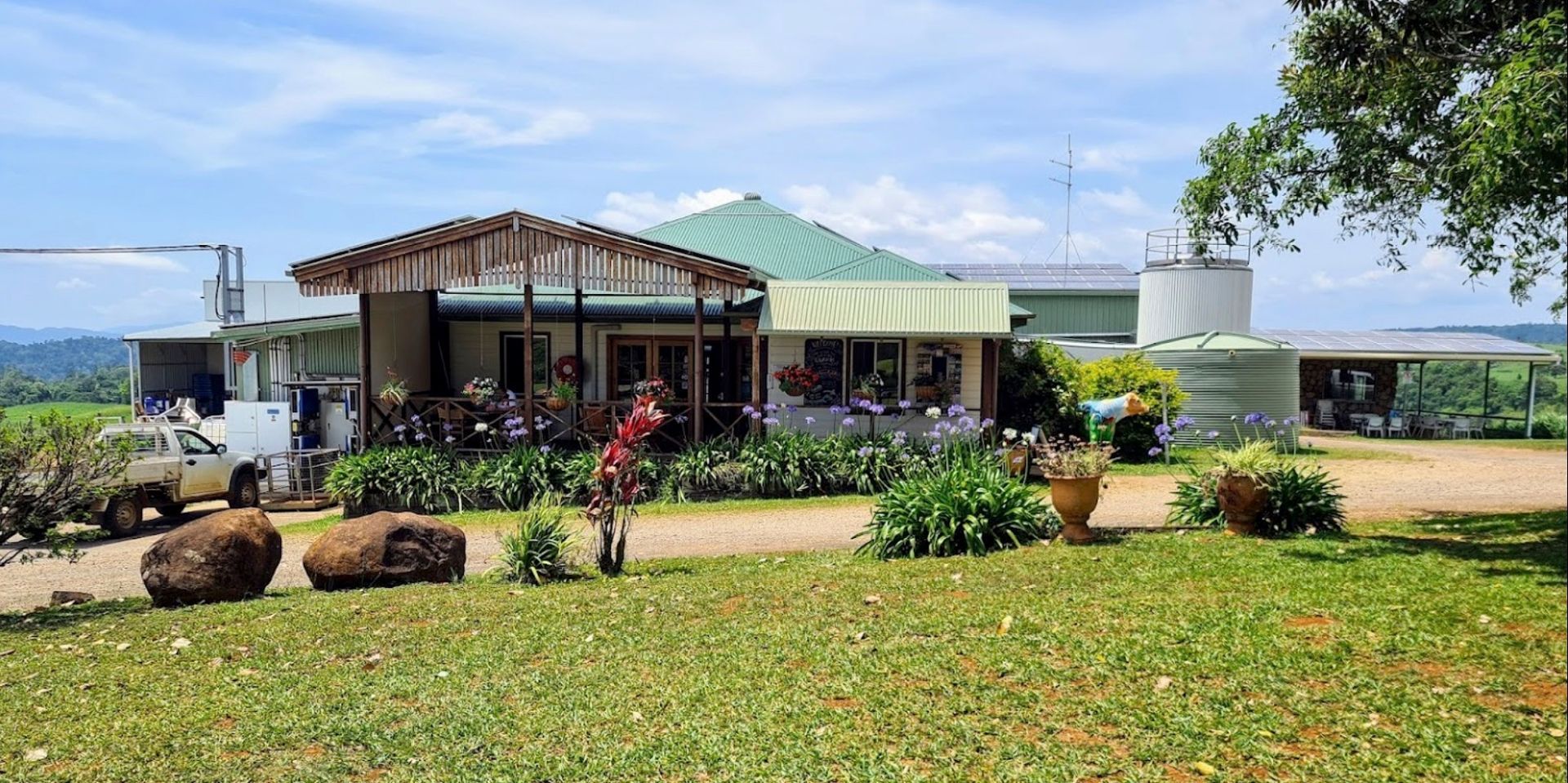 A building with a green roof surrounded by greenery and a grassy yard.