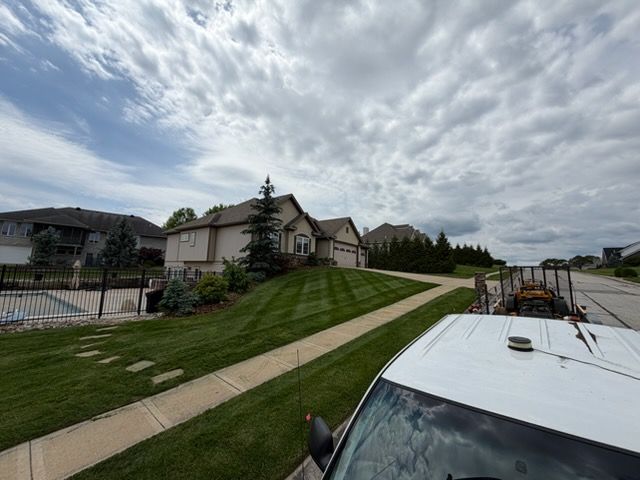 Apartment buildings and a grassy slope under a cloudy sky, with a car roof in the foreground.