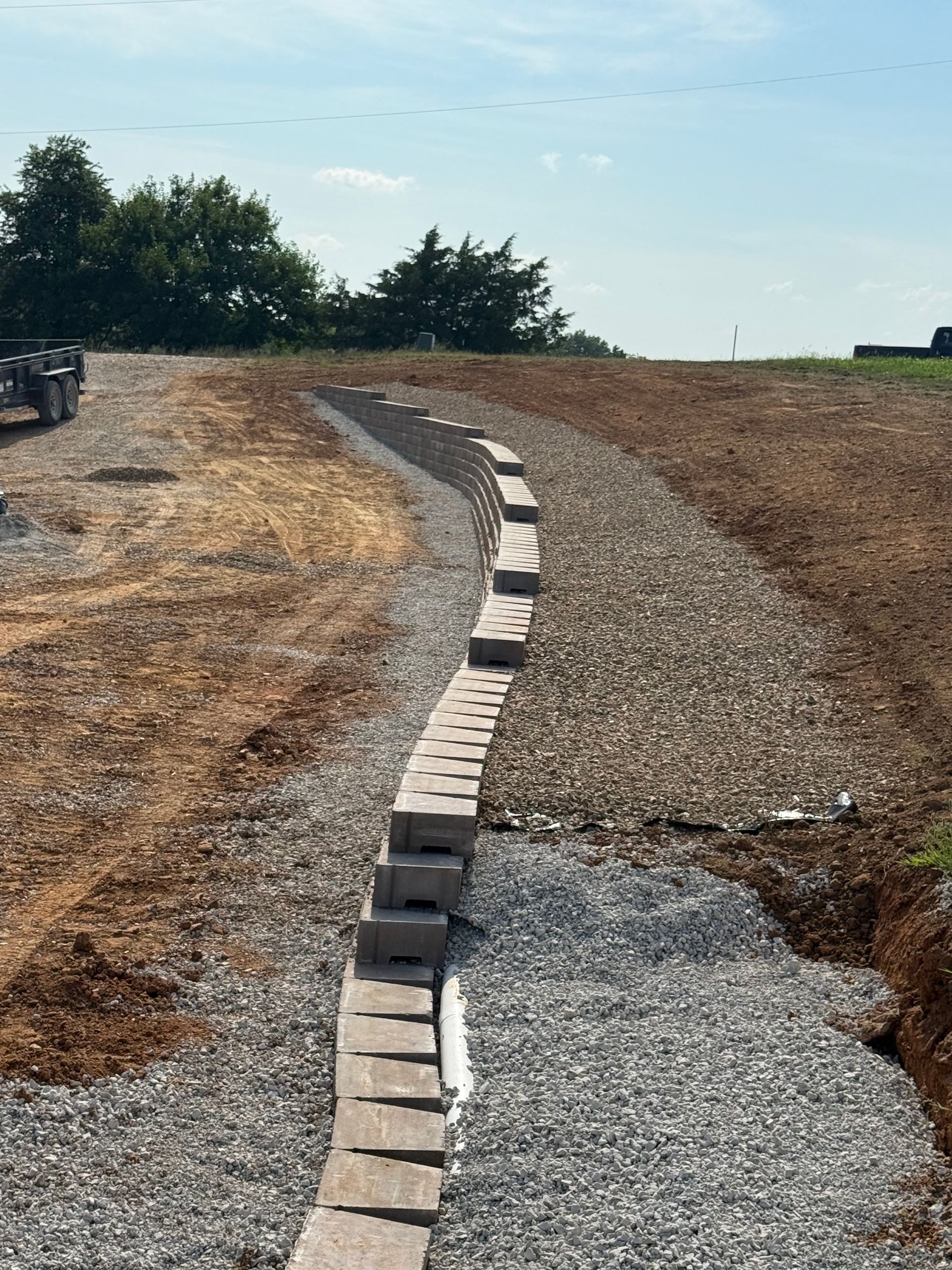 Gravel path with a curved line of concrete blocks in a dry, open landscape under a clear sky