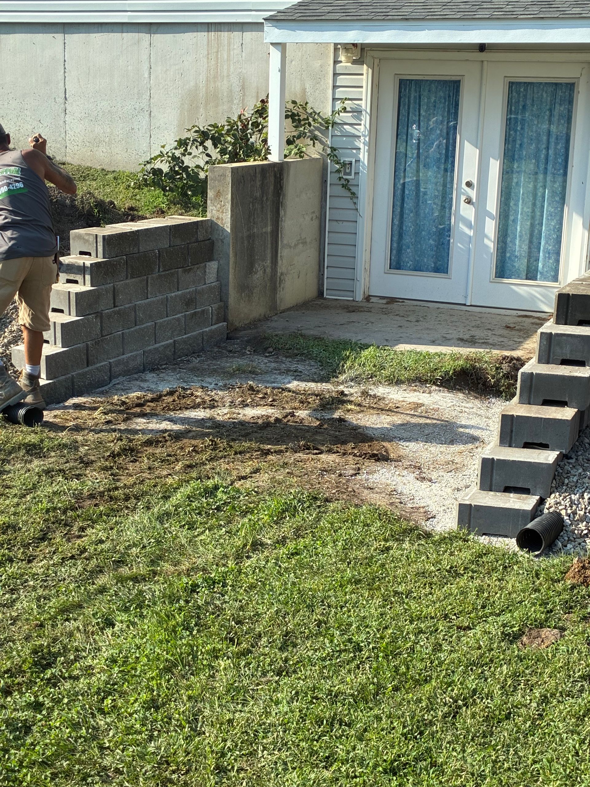 Person walking up a stone path toward white double doors in a backyard garden area