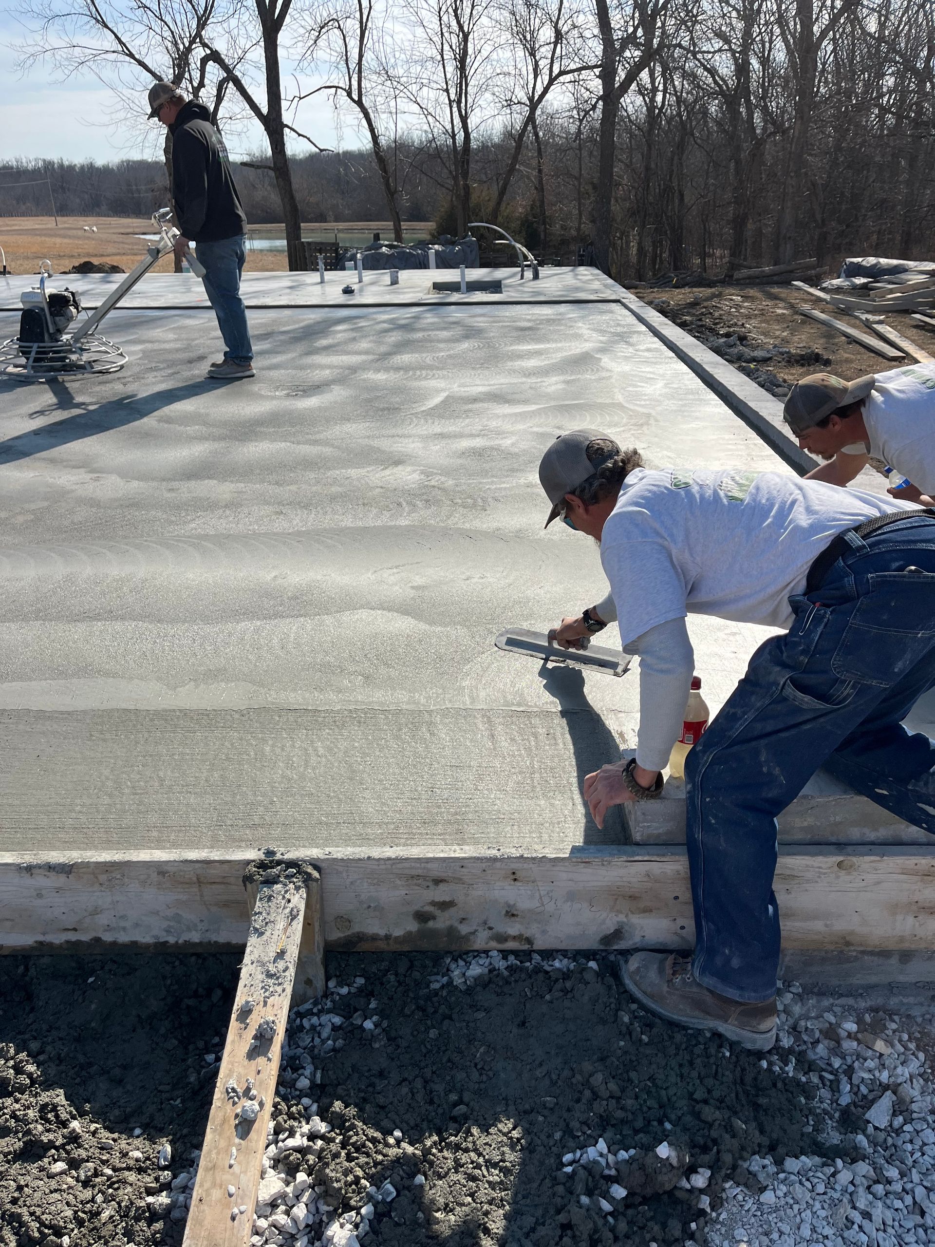 Workers finishing a concrete slab on a construction site, smoothing the surface by hand