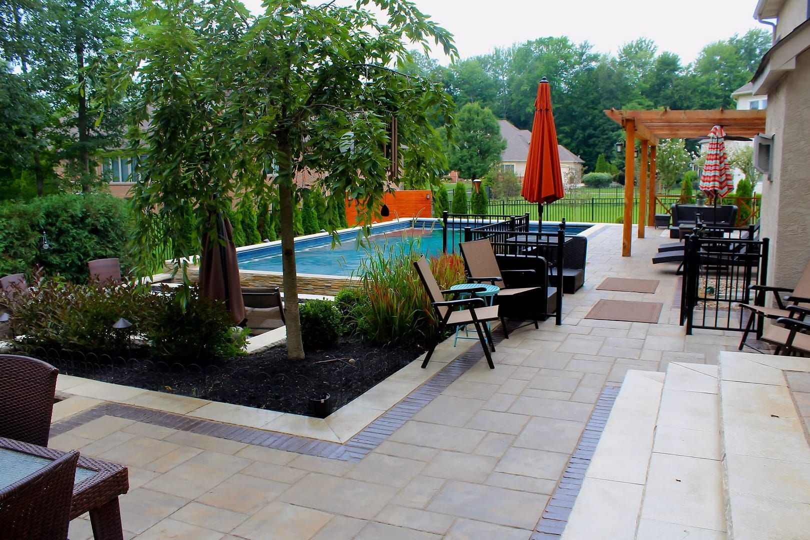 Patio seating beside a garden pool with umbrellas and stone walkway