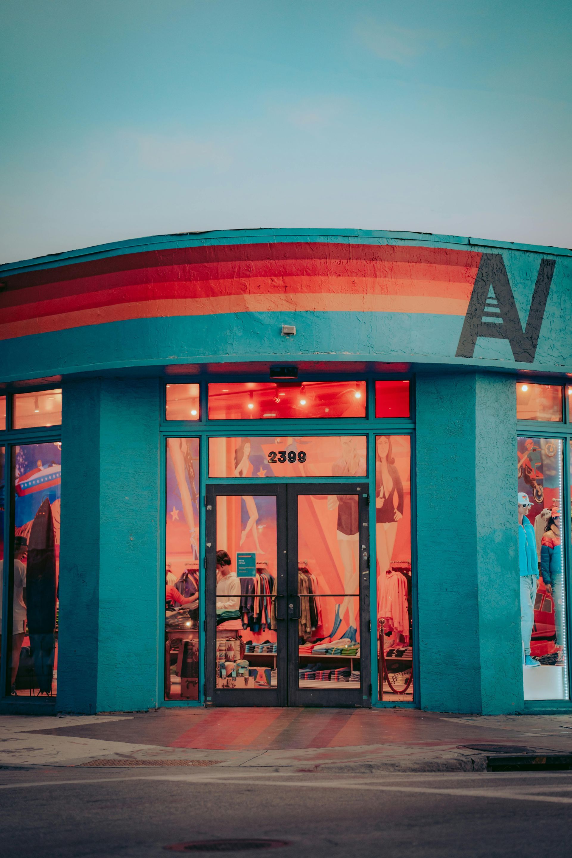 Colorful storefront with turquoise walls, red awning, and glass entrance at dusk