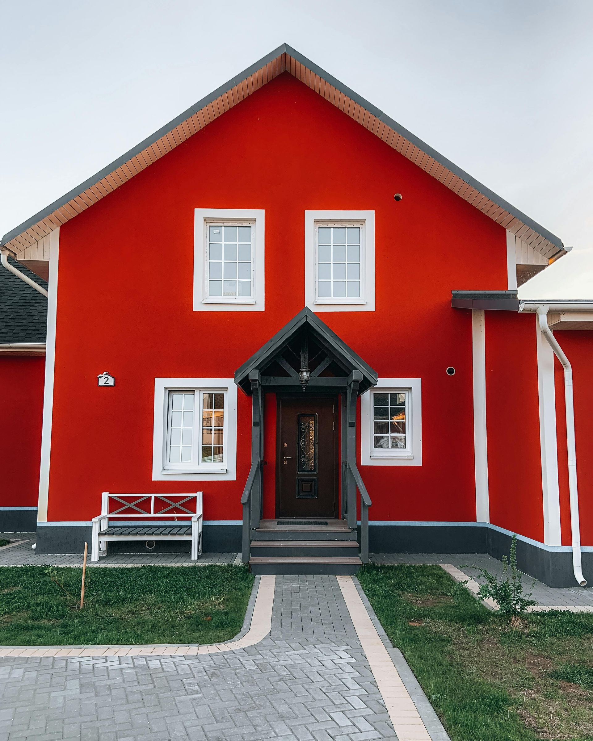 Bright red house with white trim, central front door, and a paved walkway in front