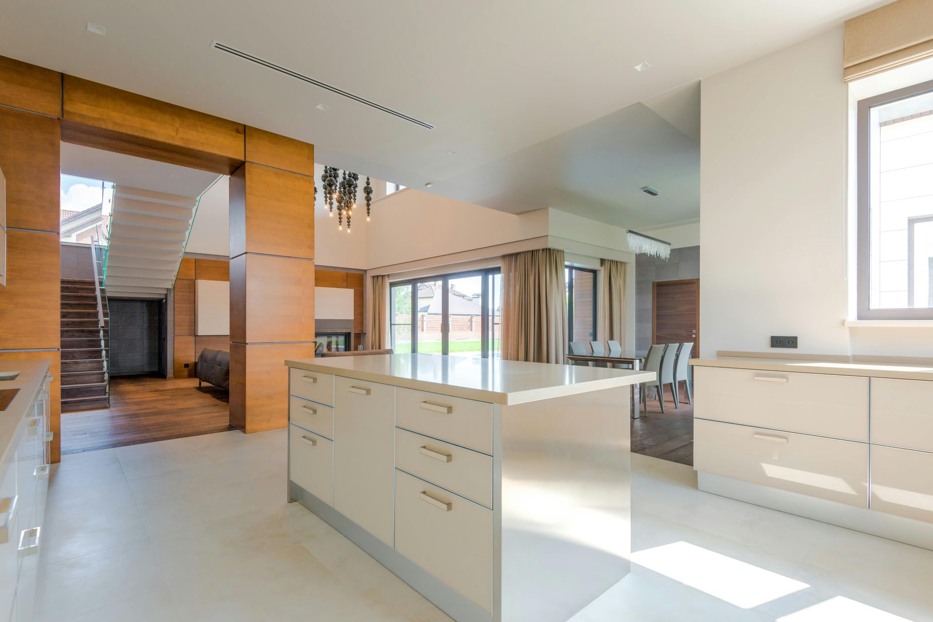 Bright modern kitchen with white cabinets, island, wood accents, and large windows