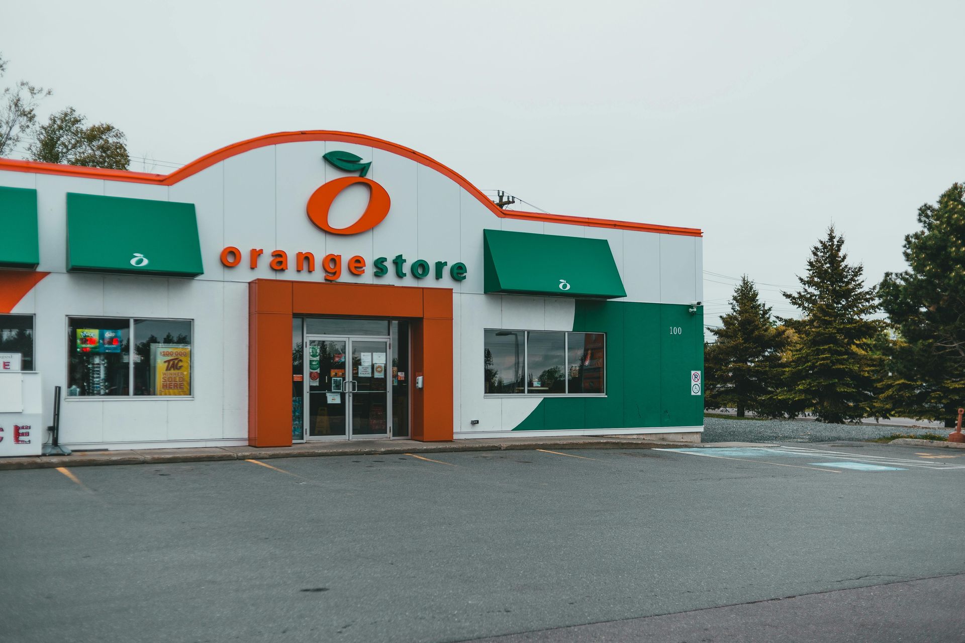 Orange store storefront with green awnings on a snowy, empty parking lot