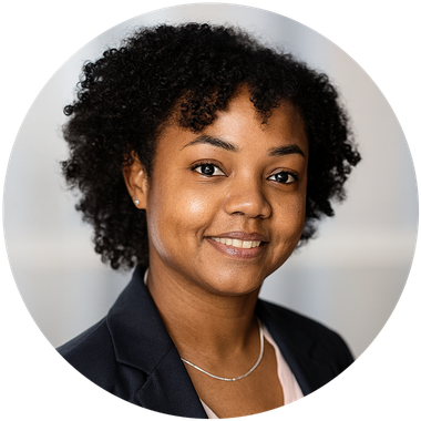 Smiling Black woman with curly hair, wearing a blazer and necklace.