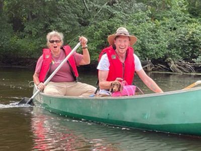 A man and a woman are rowing a canoe on a river.