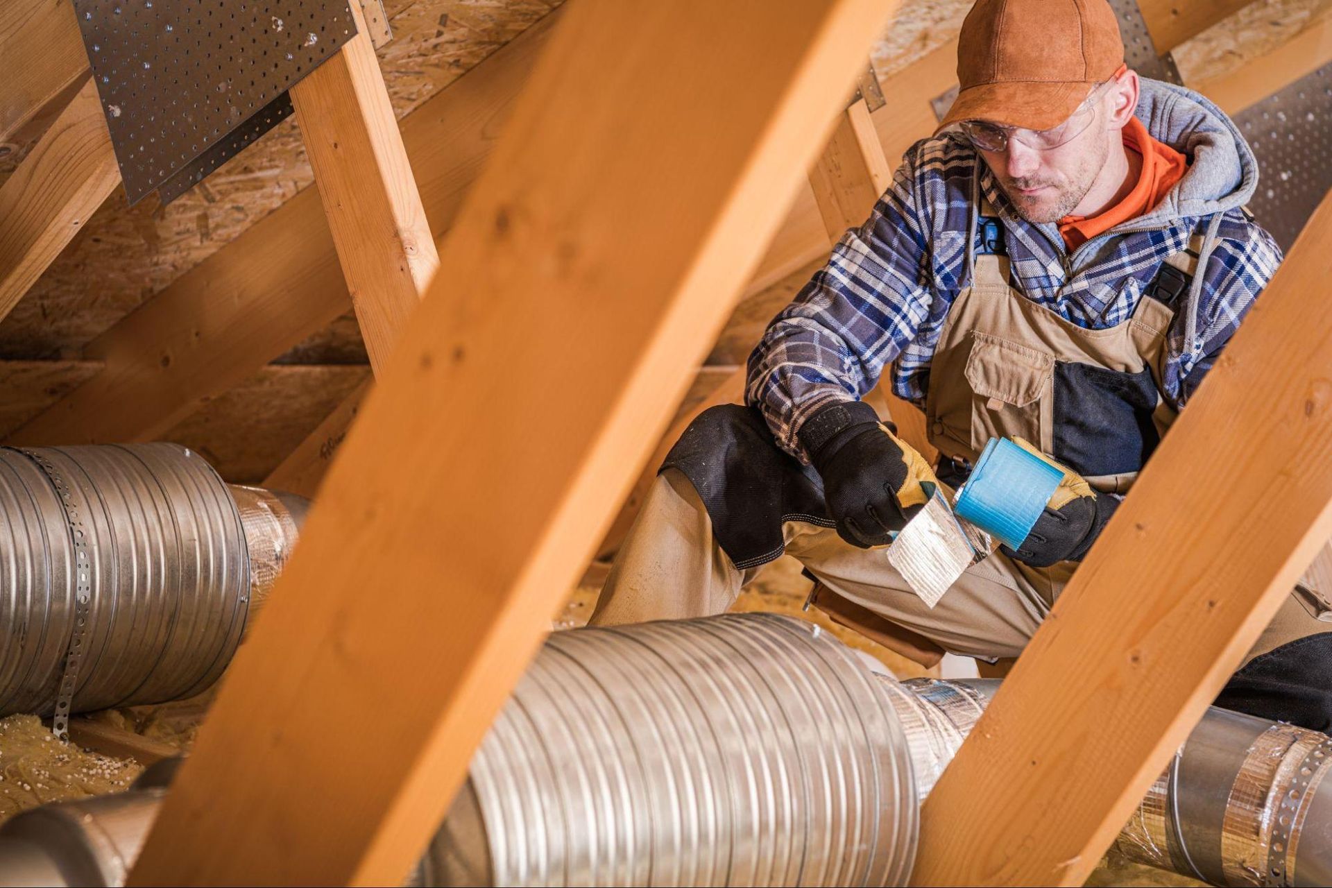 Professional sealing HVAC ductwork in an attic to help reduce air leaks and improve energy efficiency.