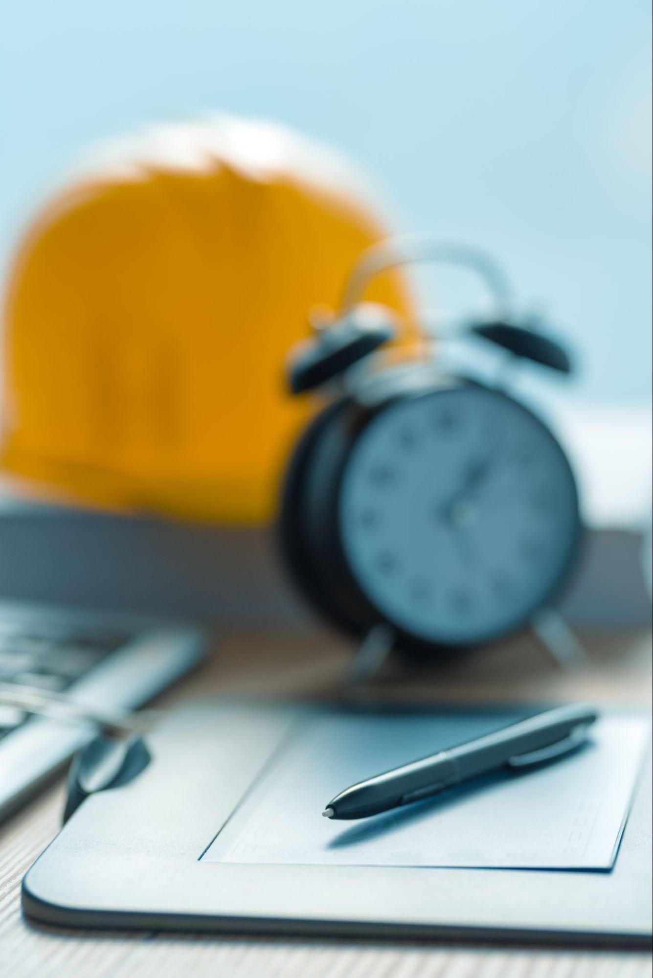Hard hat and alarm clock representing timely planning for an accessibility inspection project.