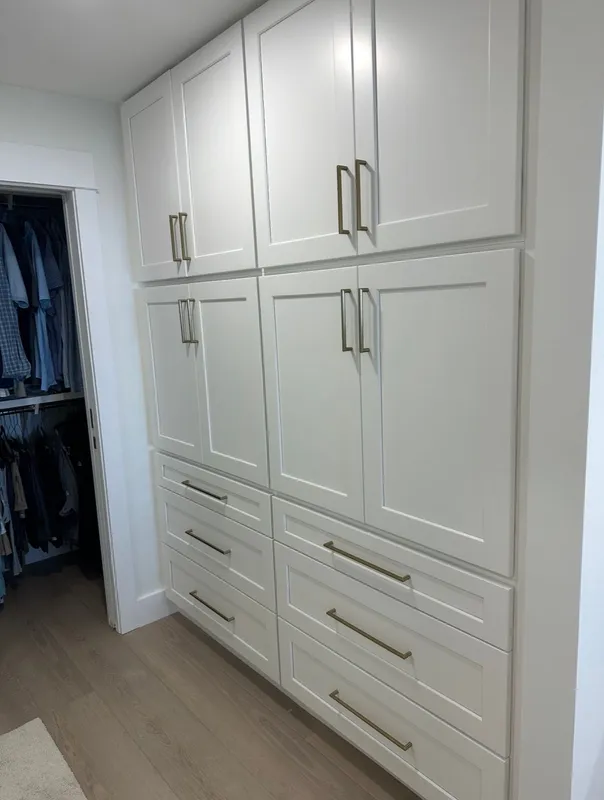 White built-in closet cabinets with drawers in a hallway