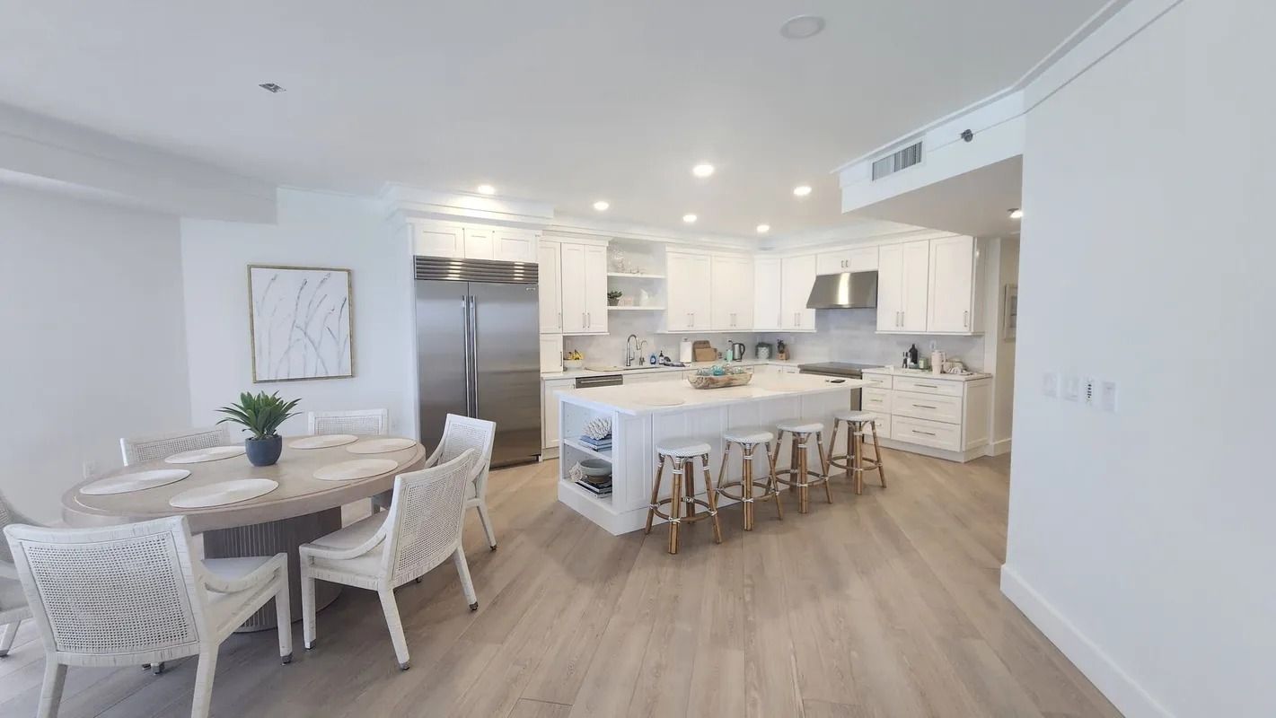 Bright open-plan kitchen and dining area with white decor, wood floors, and a round table with chairs