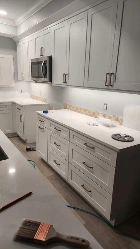 Bright modern kitchen with white cabinets, gray island, and stainless steel microwave and sink.