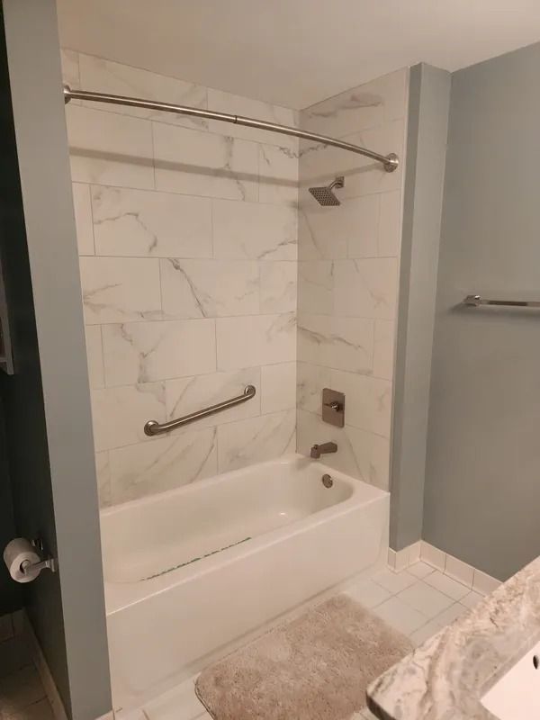 Accessible bathroom shower with bench, grab bars, and hand-held showerhead