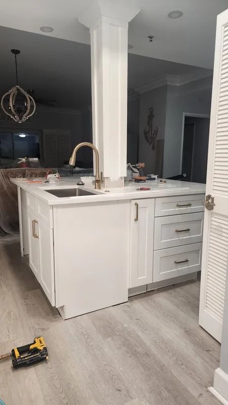 Kitchen island with white cabinetry, sink, and gold faucet in a modern open-plan home
