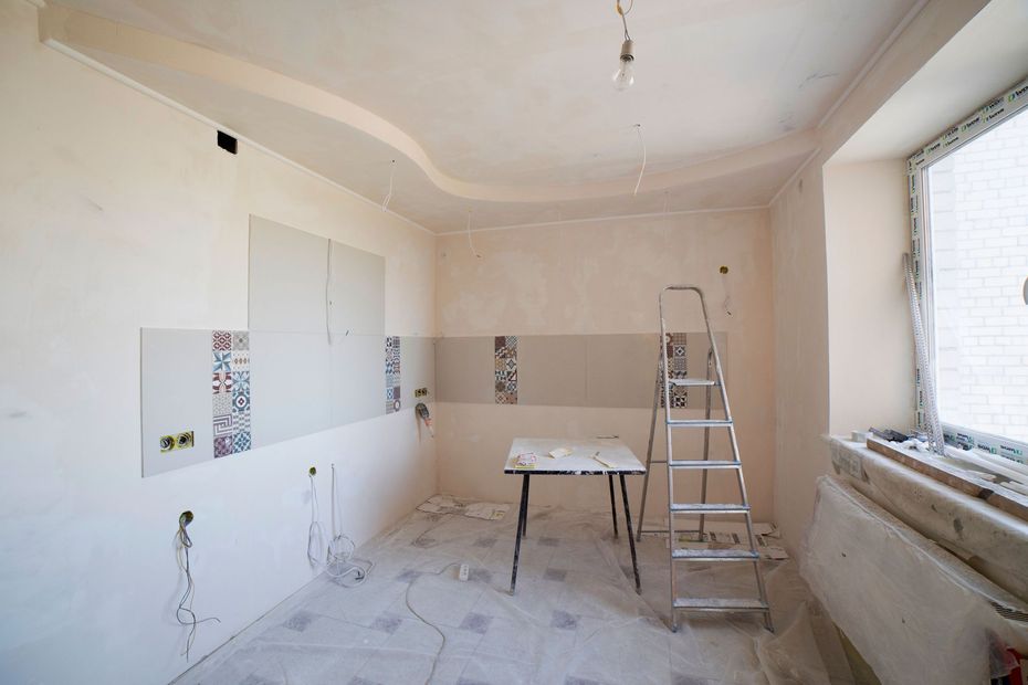 Renovation in progress in a bright room with ladder, work table, and unfinished walls