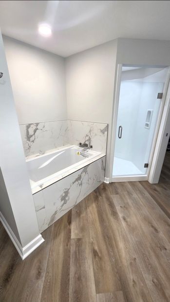 Modern bathroom with white vanity, marble accents, and wood-look flooring