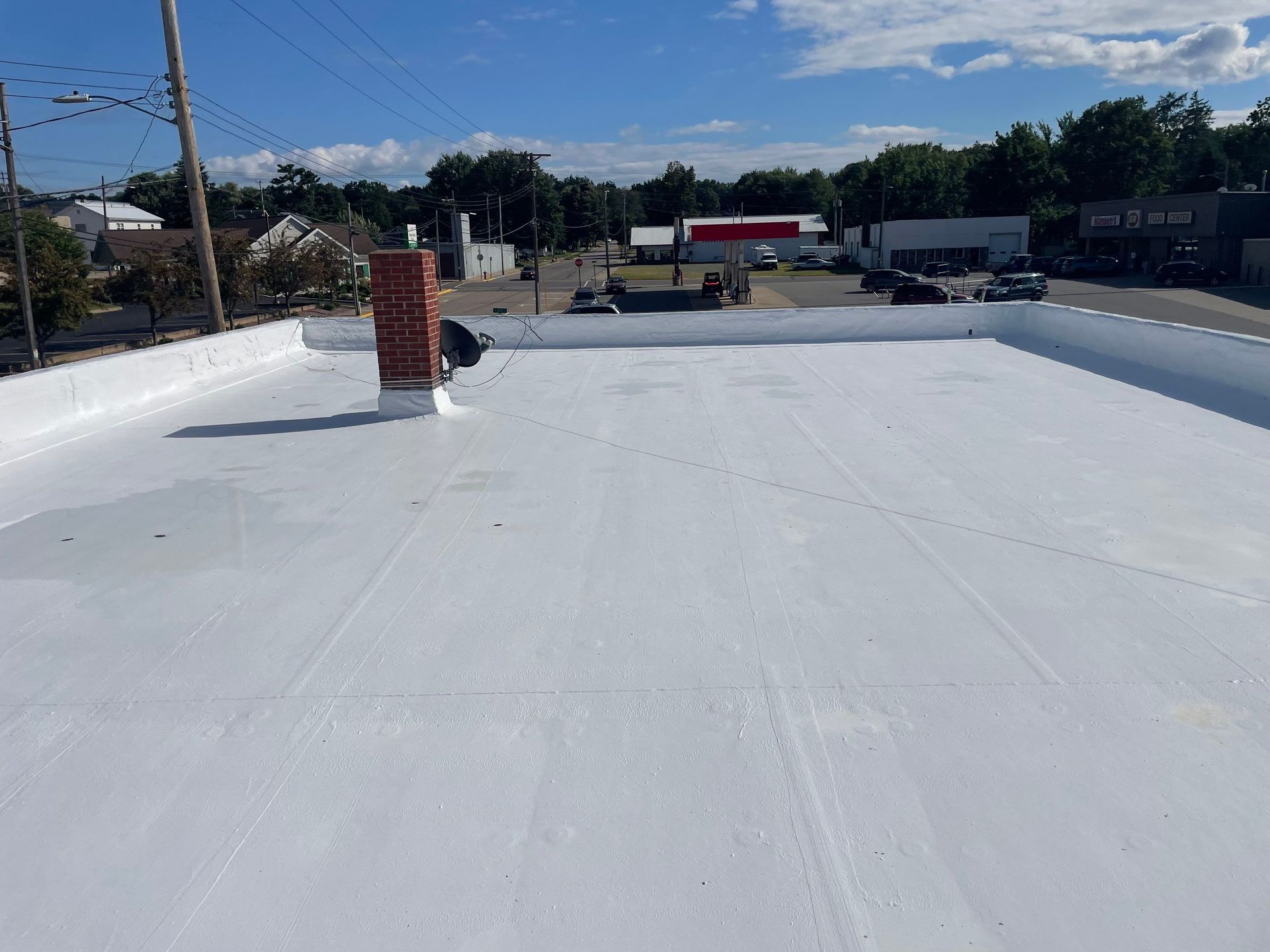 White flat roof with brick chimney against a blue sky.