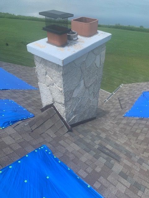 A stone chimney is sitting on top of a brick roof.