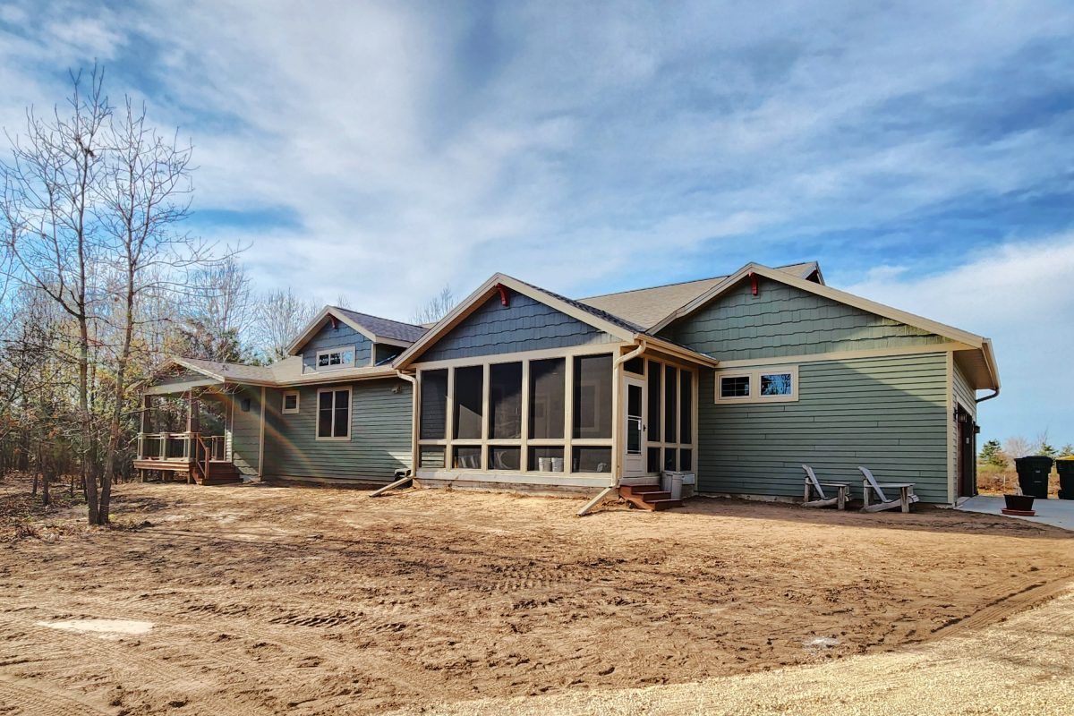 A large house with a screened in porch in the backyard.
