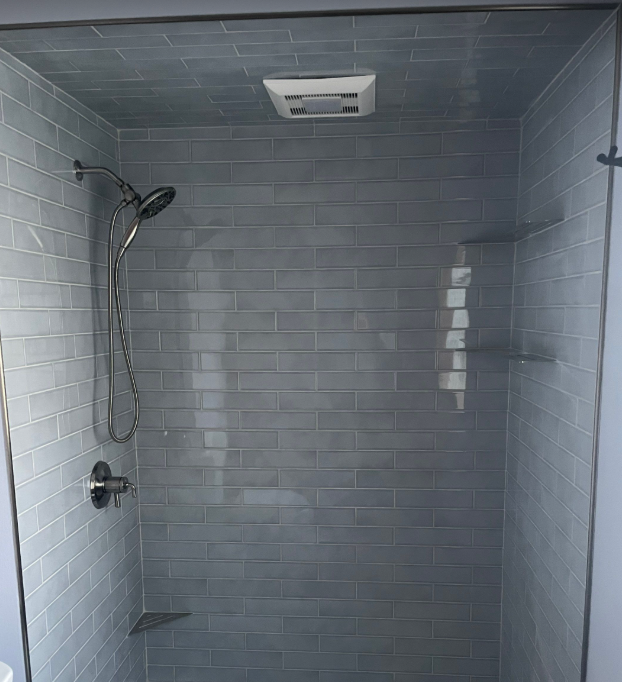 There is a shower with a glass door and a shower head.