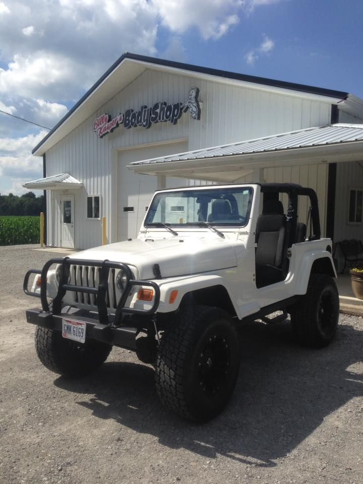 White Jeep Wrangler parked in front of a white building with