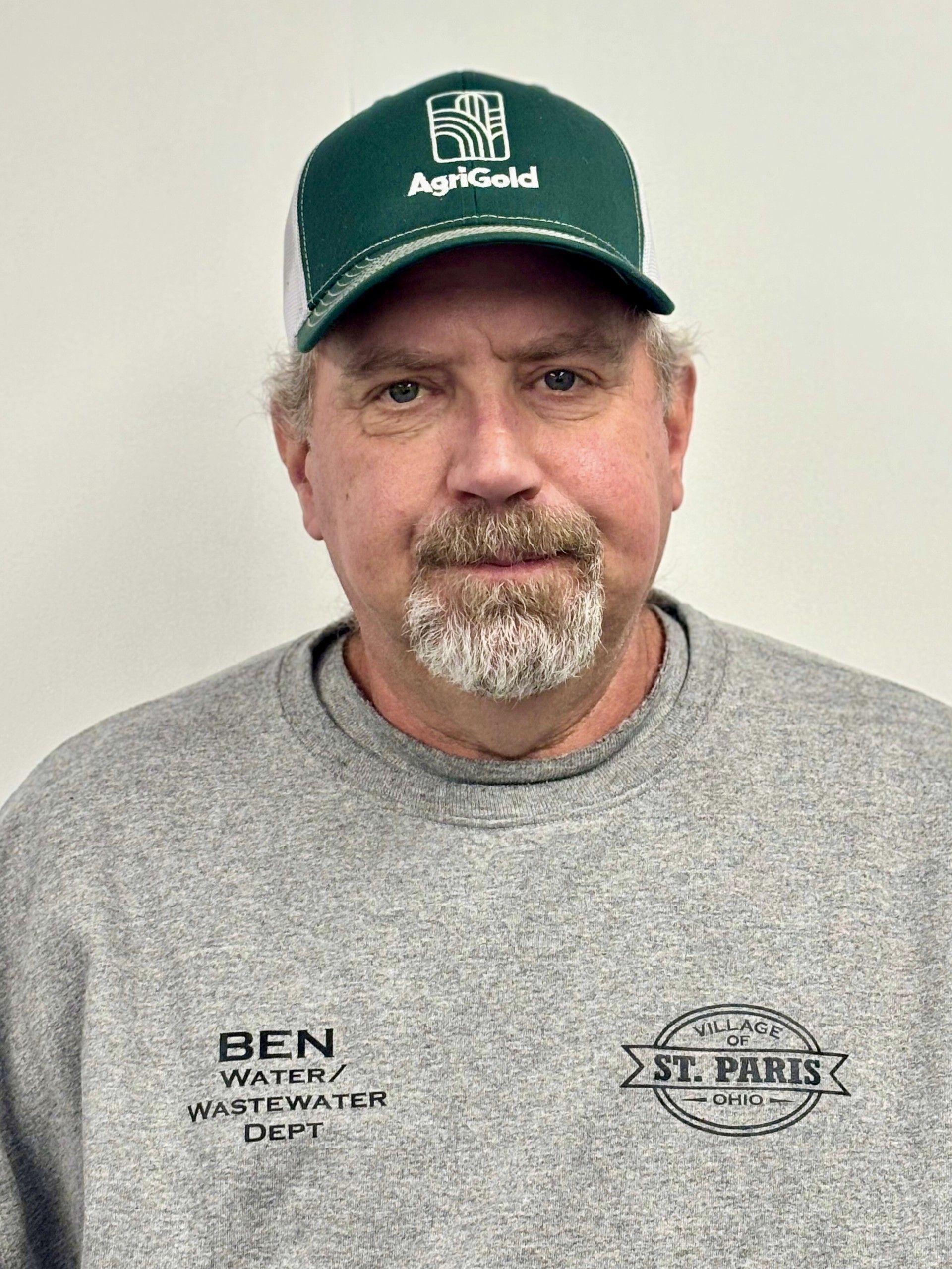 Man wearing a green and white cap, gray sweatshirt. Cap reads