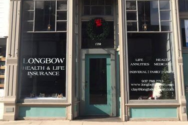Exterior of Longbow Health & Life Insurance office, with glass windows, teal door, and wreath.
