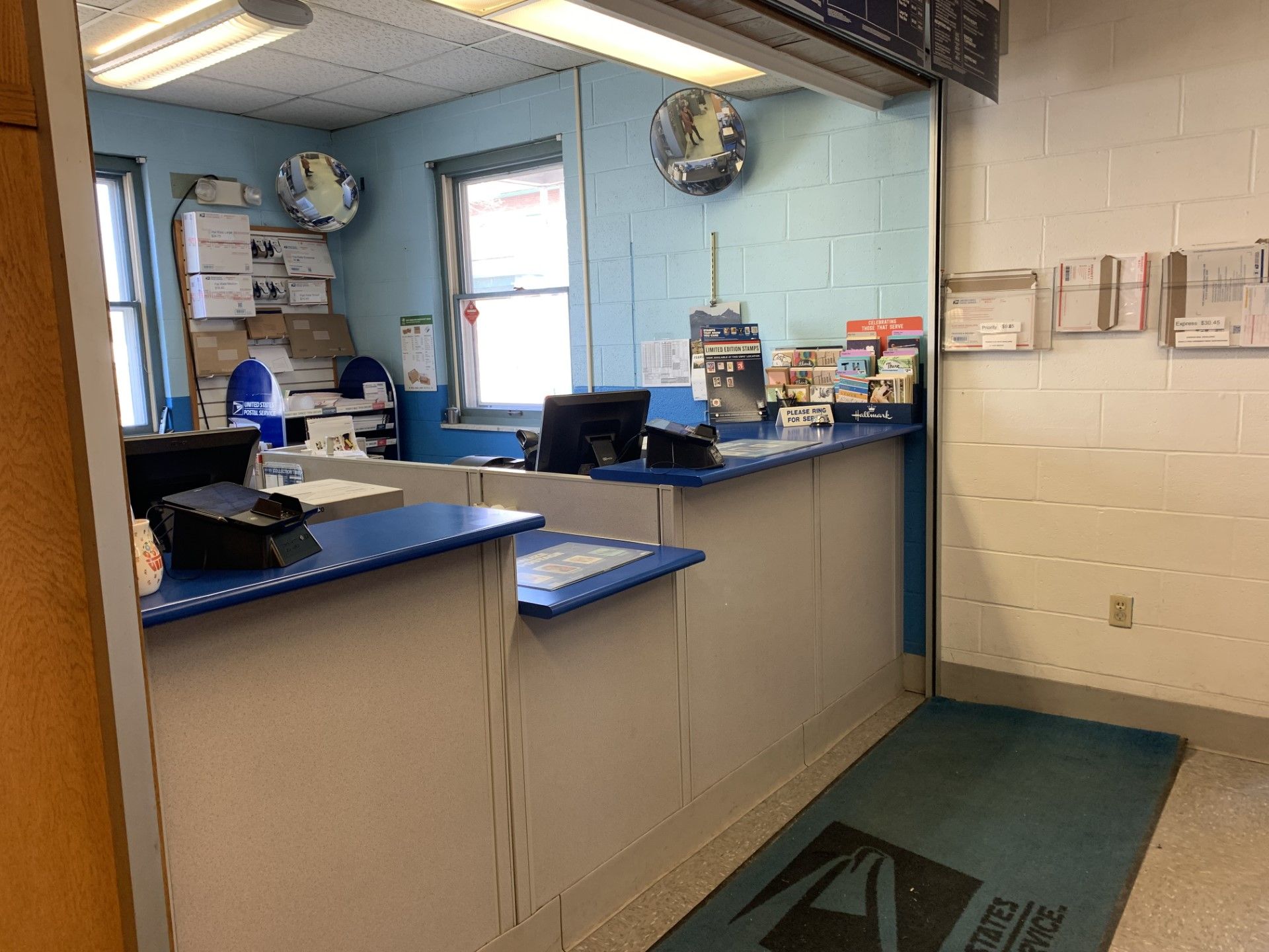 Post office interior with counter, blue accents, and a USPS welcome mat.